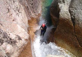 A woman is abseiling down a waterfall during a Canyoning in Canyon de Pulischellu - Discovery tour with Corsica Madness.
