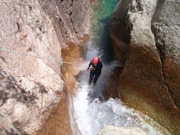 Une femme descend en rappel le long d'une cascade pendant une sortie Canyoning dans le canyon de Pulischellu - Découverte avec Corsica Madness.