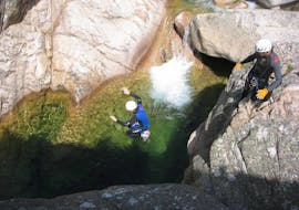 A man is jumping in a natural pool during a Canyoning in Canyon de la Vacca - Aquatic trip with Corsica Madness.