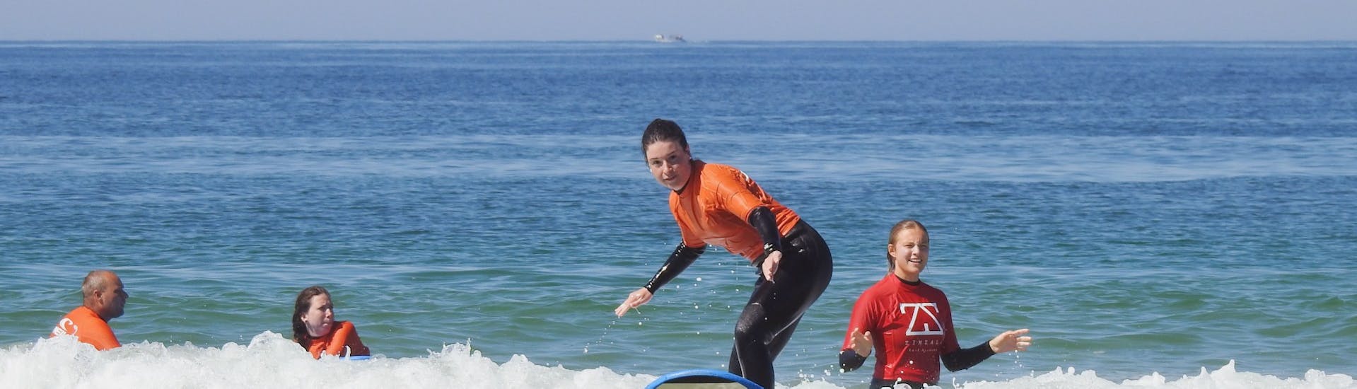 A girl riding a wave during the surfing lessons in Albufeira for beginners with Albufeira Surf & SUP.