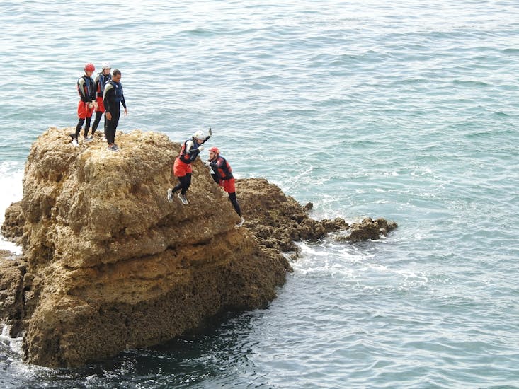 A man jumping from a cliff while Coasteering in Albufeira - Coastal Adventures with Albufeira Surf & SUP.