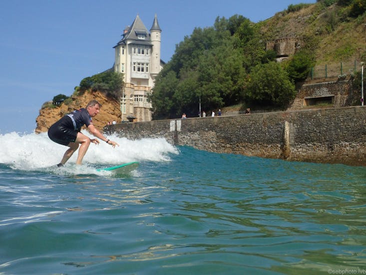 Un surfista se prepara para cabalgar una ola durante unas clases particulares de surf en la playa de Côte des Basques con La Vague basque.