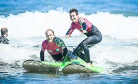 2 hombres están aprendiendo a surfear gracias a una lección de surf para Niños & Adultos con ocean beach en Hendaya.