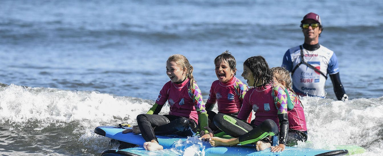 4 girls sit on a surf on the sea for a surfing lesson near their instructor of ocean beach in Hendaye.
