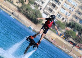 Une personne debout sur une planche au-dessus de l'eau lors d'une séance de Flyboard dans la baie de Spinola à St. Julian's avec Flyboard Malta Ltd.