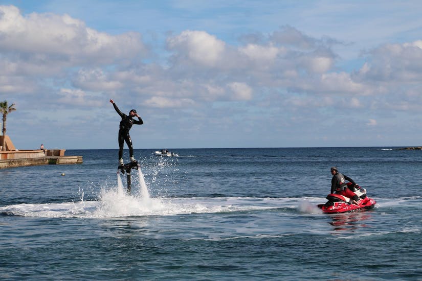 Een persoon staat op een board boven het water tijdens het Flyboarden in Spinola Bay in St. Julian's met Flyboard Malta Ltd.