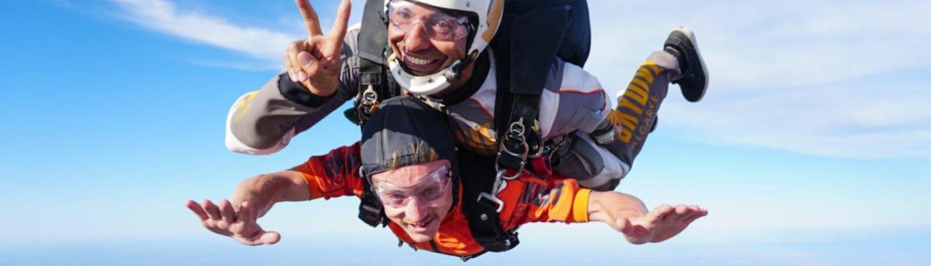 Der Instruktor posiert für die Kamera, während er beim Tandemsprung aus 10.000 Fuß - Algarve mit Skydive Algarve fällt.
