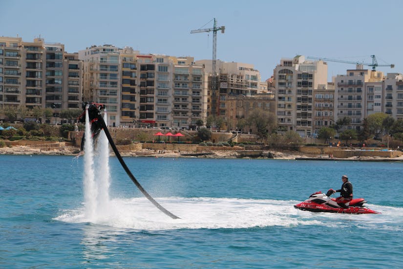 A person standing on a board above the water during Flyboarding in Spinola Bay in St. Julian's with Flyboard Malta Ltd.