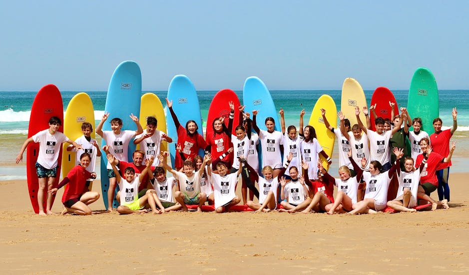 Surfers are taking a group picture after their Surf Lessons for Kids (4-10 y.) on Lacanau Centrale Beach with Hurley Surf Club in Lacanau.