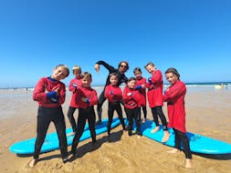 Eine Gruppe von Kindern posiert für ein Foto mit ihrem Surflehrer während ihres Surfunterrichts am Strand von Sablères mit der Surfschule ESCF Vieux Boucau.