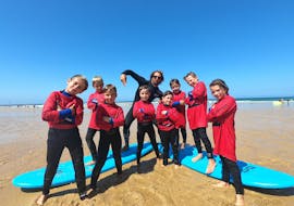 A group of kids is posing for a picture with their surfing instructor during their Surfing Lessons on the Sablères Beach with the surf school ESCF Vieux Boucau.