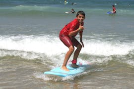 A surfer is happy to stand on his surfboard thanks to his private surfing lessons on the beach of Sablères with the ESCF Vieux Boucau surf school.