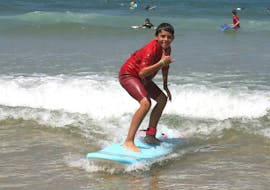 A surfer is happy to stand on his surfboard thanks to his private surfing lessons on the beach of Sablères with the ESCF Vieux Boucau surf school.