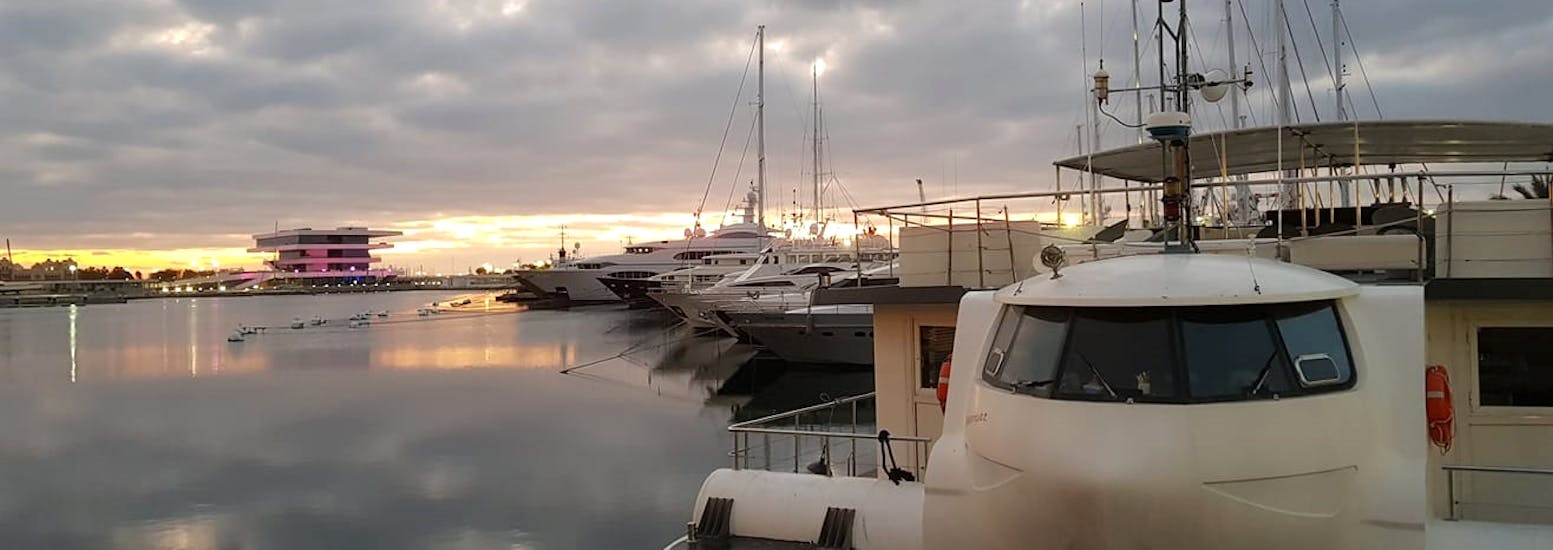 Un barco bajo la puesta de sol durante un paseo en barco por la Marina de Valencia con Boramar Valencia.