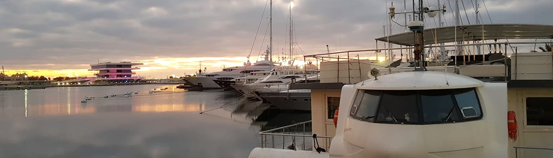 Un barco bajo la puesta de sol durante un paseo en barco por la Marina de Valencia con Boramar Valencia.