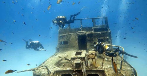 Wracktauchen in Malta für zertifizierte Taucher mit DiveWise Malta Zwei Taucher erkunden die Umgebung eines Schiffswracks während des Wracktauchens um Malta für zertifizierte Taucher mit DiveWise Malta.