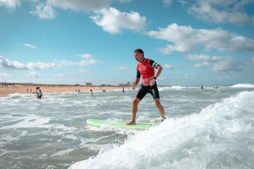 Un surfeur est heureux de se tenir debout sur sa planche de surf grâce à son cours de surf sur la plage de la Gravière avec l'école de surf ESCF Hossegor.