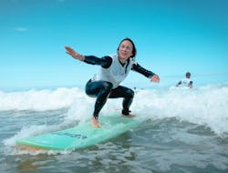 A surfer is taking a small wave on the shore thanks to her private surfing lessons on the Gravière Beach with ESCF Hossegor surf school.