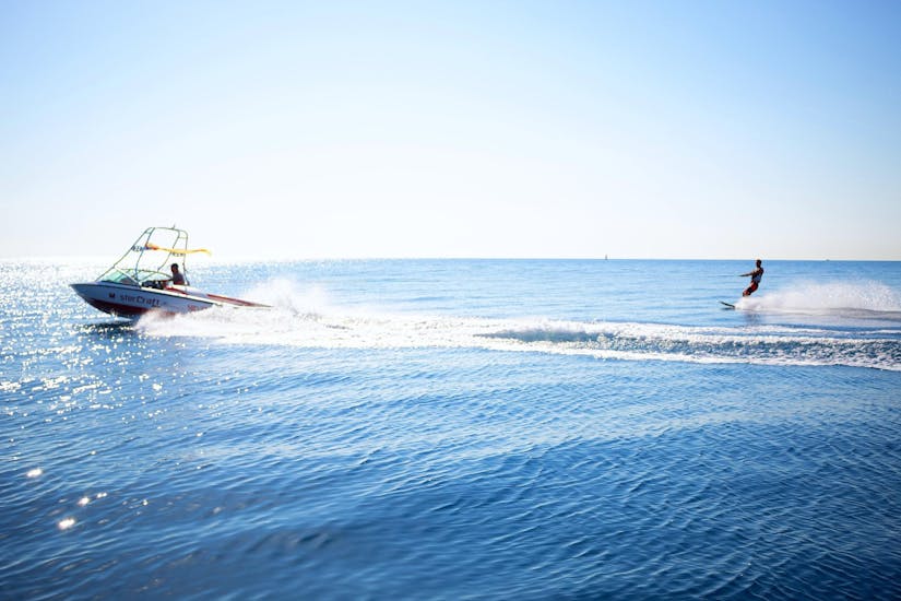 A man is being towed by a boat while Waterskiing in Villeneuve-Loubet with Plage des Marines.