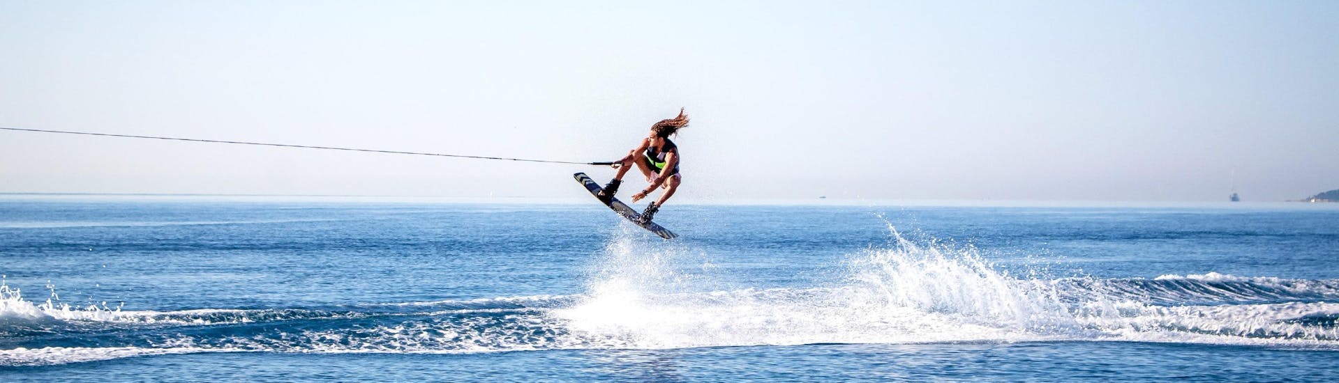 A man is doing a jump during his Wakeboarding & Wakesurfing tour in Cagnes-sur-Mer with Plage des Marines.