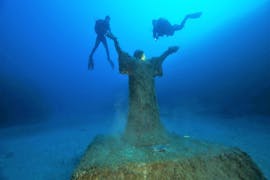 Dos buceadores exploran el mar alrededor de la estatua sumergida del Cristo del Abismo en Malta durante una de las inmersiones guiadas en playa y barco desde Saint Paul's Bay con Octopus Garden.