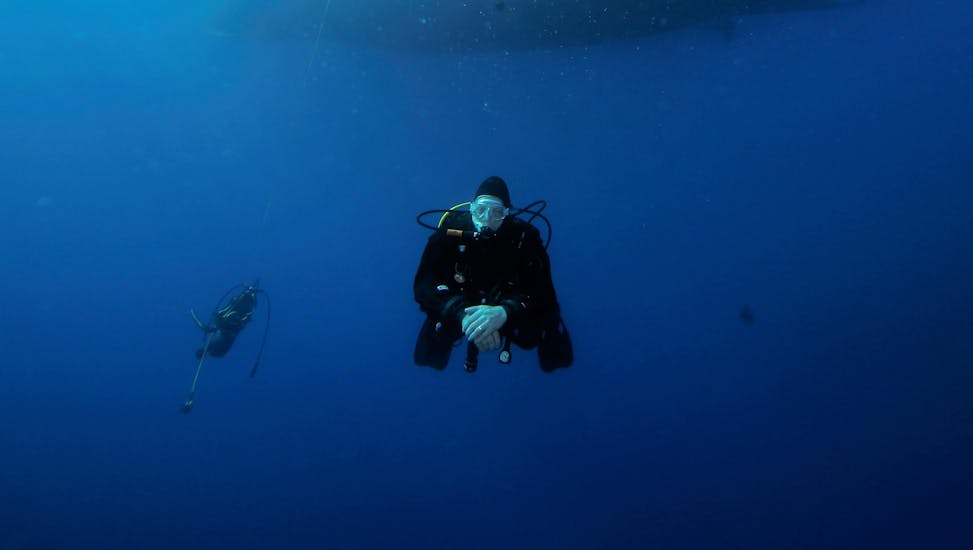 Een deelnemer aan de Scuba Duikcursus voor Beginners - SSI Open Water Diver met Octopus Garden duikt in de blauwe oceaan rond Malta.