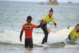 Uno studente dà il cinque all'insegnante durante le lezioni di surf per principianti (da 10 anni) a Praia da Arrifana con la Arrifana Surf School.