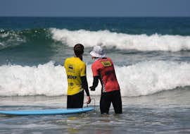 Clases particulares de surf (a partir de 7 años) con Arrifana Surf School Durante la lección privada de surf para niños y adultos, un instructor certificado de Arrifana Surf School asesora a un joven surfista sobre su técnica.