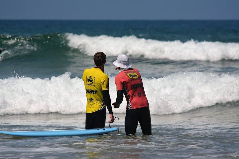 Durante la lezione privata di surf per bambini e adulti, un istruttore certificato della Arrifana Surf School consiglia un giovane surfista sulla sua tecnica.