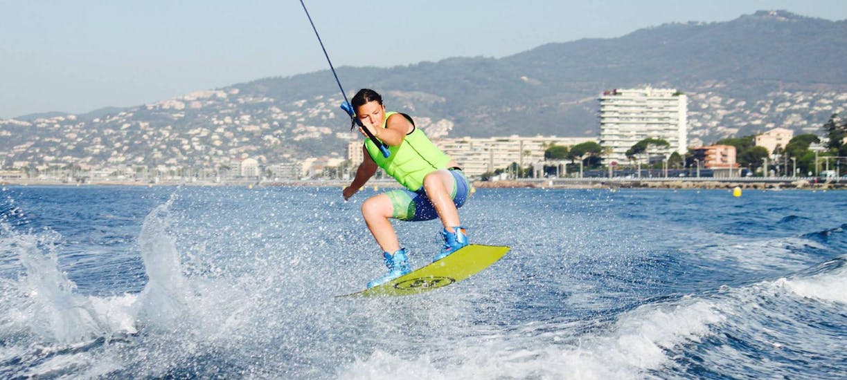Un jeune homme soulève sa planche pendant le Wakeboarding à Cannes avec Cannes Esprit Glisse.