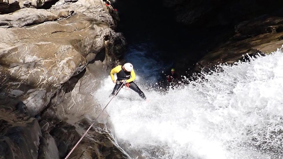 Ein Mann seilt sich bei der Tour Canyoning im Schwarzwasserbach für Erfahrene mit canyoning erleben einen tosenden Wasserfall hinunter.