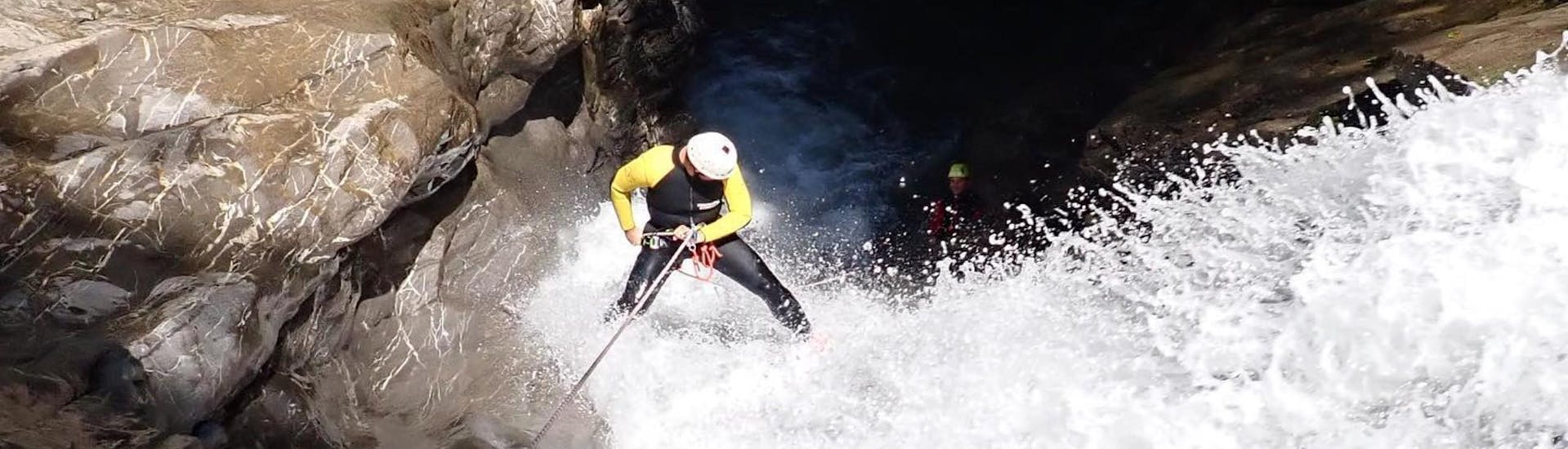Ein Mann seilt sich bei der Tour Canyoning im Schwarzwasserbach für Erfahrene mit canyoning erleben einen tosenden Wasserfall hinunter.
