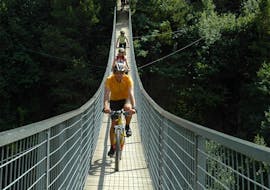 Drei Radfahrer überqueren während ihrer Mountainbike Tour auf dem Ötztal Trail mit CanKick Ötztal eine Brücke.