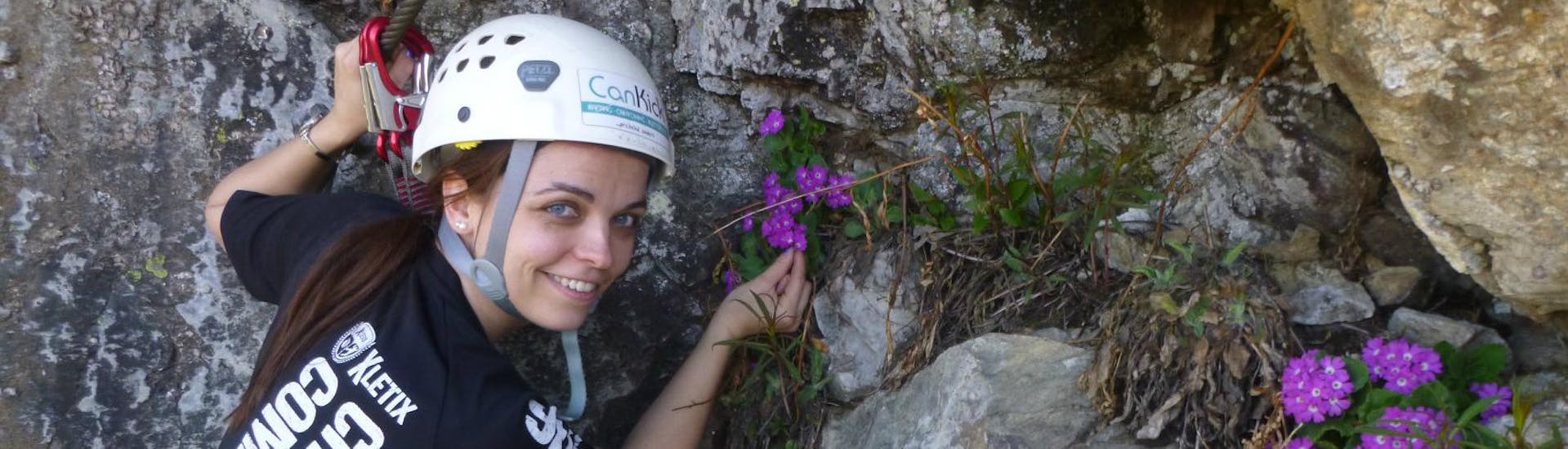 A young woman is picking flowers from the Burgsteiner Wand during her Via Ferrata in the Ötztal Valley - 'Burgsteiner Wand' with CanKick Ötztal.