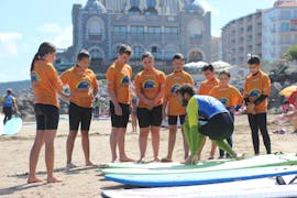 Les surfeurs sont sur la plage et écoutent les instructions de leur moniteur de surf pendant leur Cours de surf (dès 9 ans) sur la plage d'Hendaye pour Débutants avec École de Surf Hendaia.