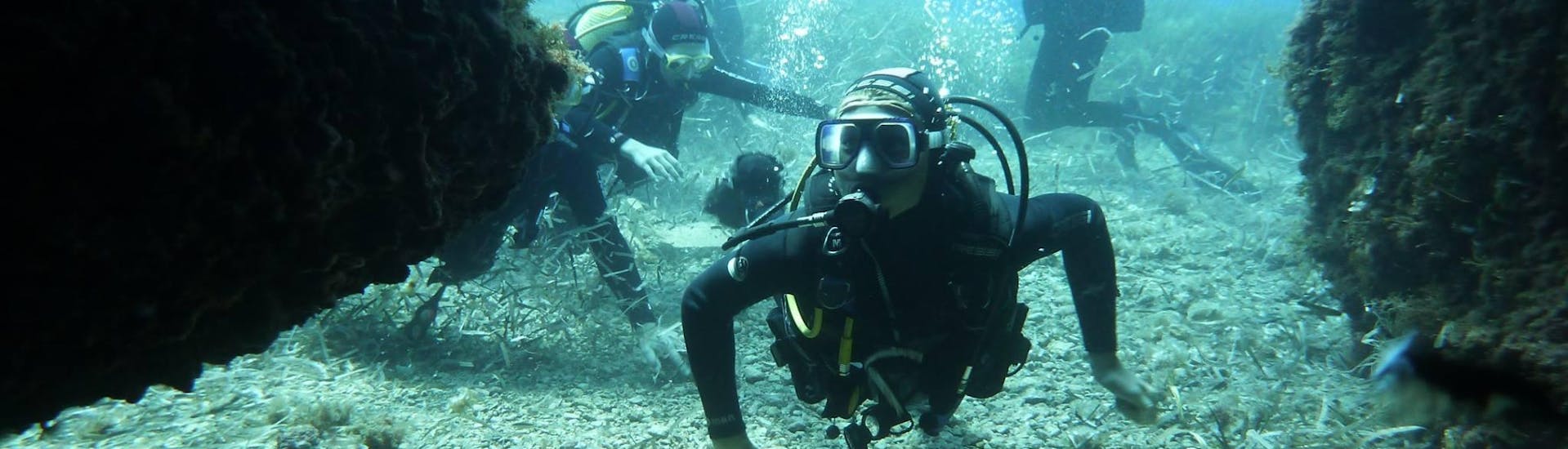 Un groupe de personnes plongeant entre les rochers lors des plongées guidées à Port d'Andratx pour les plongeurs certifiés de Balear Divers.
