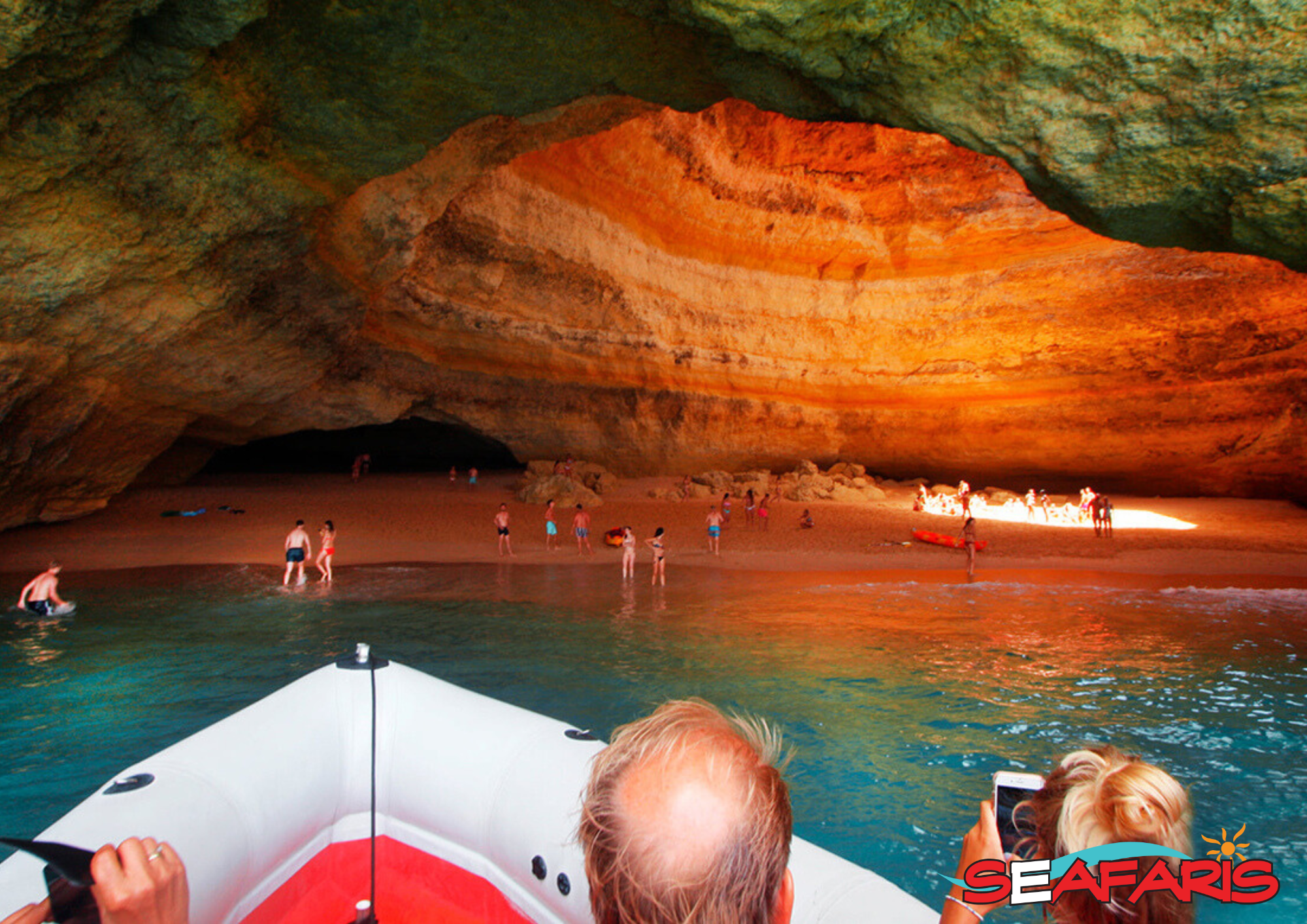 Dolphin Seafaris boat tour inside the sunlit Benagil Cave The Dolphin Seafaris Algarve boat approaches the sandy beach inside the famous Benagil Cave, filled with visitors during the Lagos: Benagil Cave & Sea Caves Boat Tour.