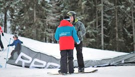 Ein Lehrer erklärt einem Schüler etwas während des Snowboardkurses für Kinder und Erwachsene (ab 10 J.) für Anfänger mit der Snowboardschule Boardstars Schladming.
