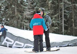Een instructeur legt iets uit aan een leerling tijdens hun snowboardlessen voor kinderen (vanaf 10 jaar) en volwassenen voor beginners bij Snowboardschule Boardstars Schladming.