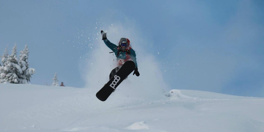 Ein Snowboarder springt während eines Freestyle Snowboarding Kurses für alle Könnerstufen mit Ausrüstung bei Boardstars Schladming.