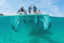 A group of certified divers dive into the water in Santa Ponsa during a guided tour offered by ZOEA Mallorca.