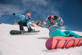 Deux enfants heureux pendant leur cours de snowboard pour enfants avec équipement à l'école de snowboard Boardstars Schladming.