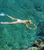 Eine Frau beim Schnorcheln im kristallklaren Wasser mit Blue Adventures Diving Chania während des Schnorchelausflug mit dem Boot von Chania