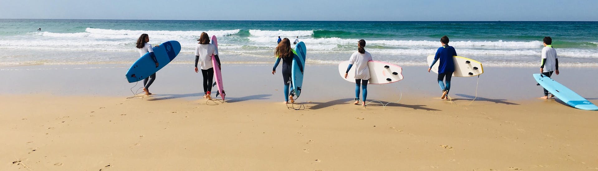 Een groep studenten gaat naar de zee om hun surflessen voor alle niveaus vanaf 8 jaar te krijgen met It's On Surf School.