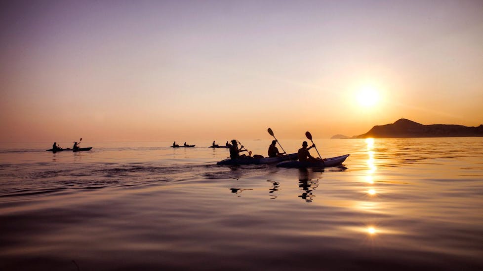Alcune persone in kayak durante il kayak in mare al tramonto all'isola di Lokrum a Dubrovnik con X-Adventure Sea Kayaking Dubrovnik.