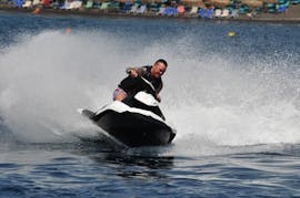 Ein Mann fährt mit voller Geschwindigkeit auf dem Jet Ski am Perissa oder Perivolos Strand in Santorini mit Wavesports Santorini.