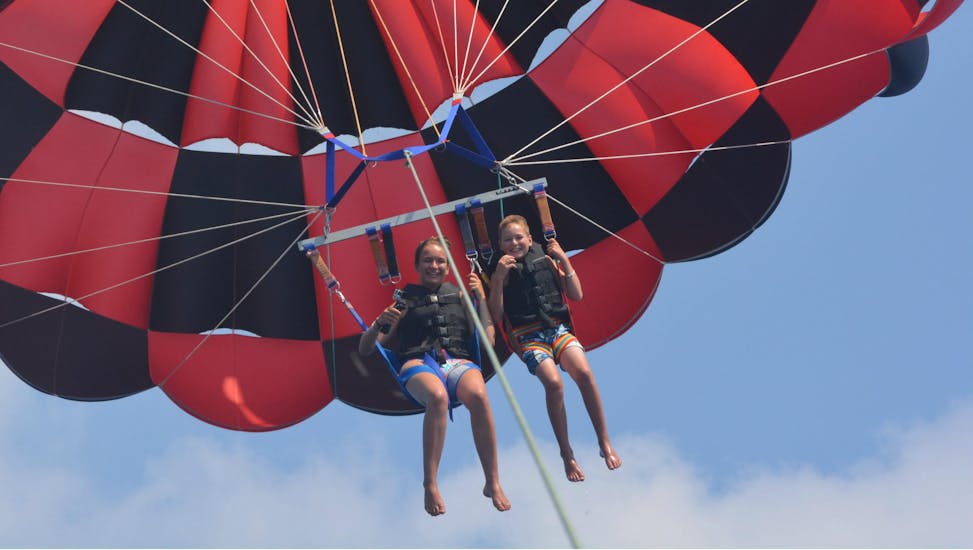 De jeunes enfants s'amusent à faire du parachute ascensionnel sur la plage de Perissa ou Perivolos à Santorin avec Wavesports Santorini.