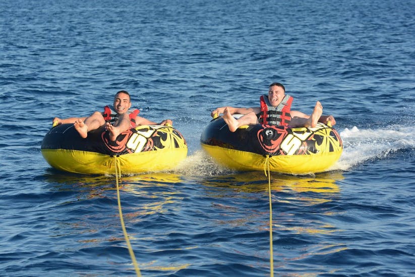 Deux jeunes hommes font l'expérience du Crazy Squab & Ringos Rides à Perissa ou Perivolos à Santorini avec Wavesports Santorini.