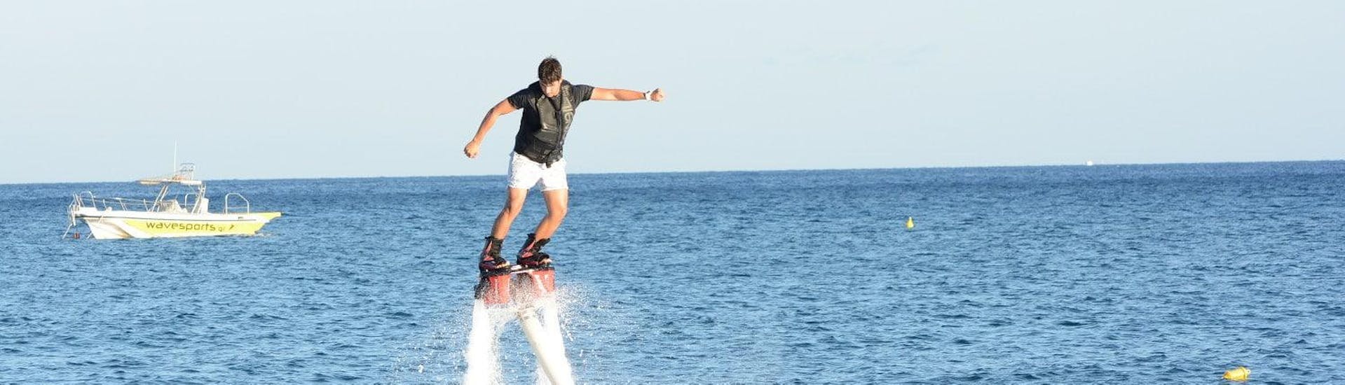 Un jeune homme est sur le flyboard pendant le Flyboarding sur la plage de Perissa ou Perivolos à Santorini avec Wavesports Santorini.