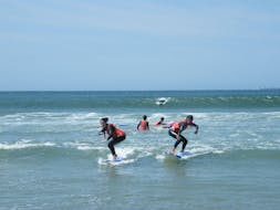 Deux jeunes filles apprendent à surfer pendant des cours de surf sur la plage de Matosinhos sous la supervision d'un moniteur de surf certifié de Surfaventura.